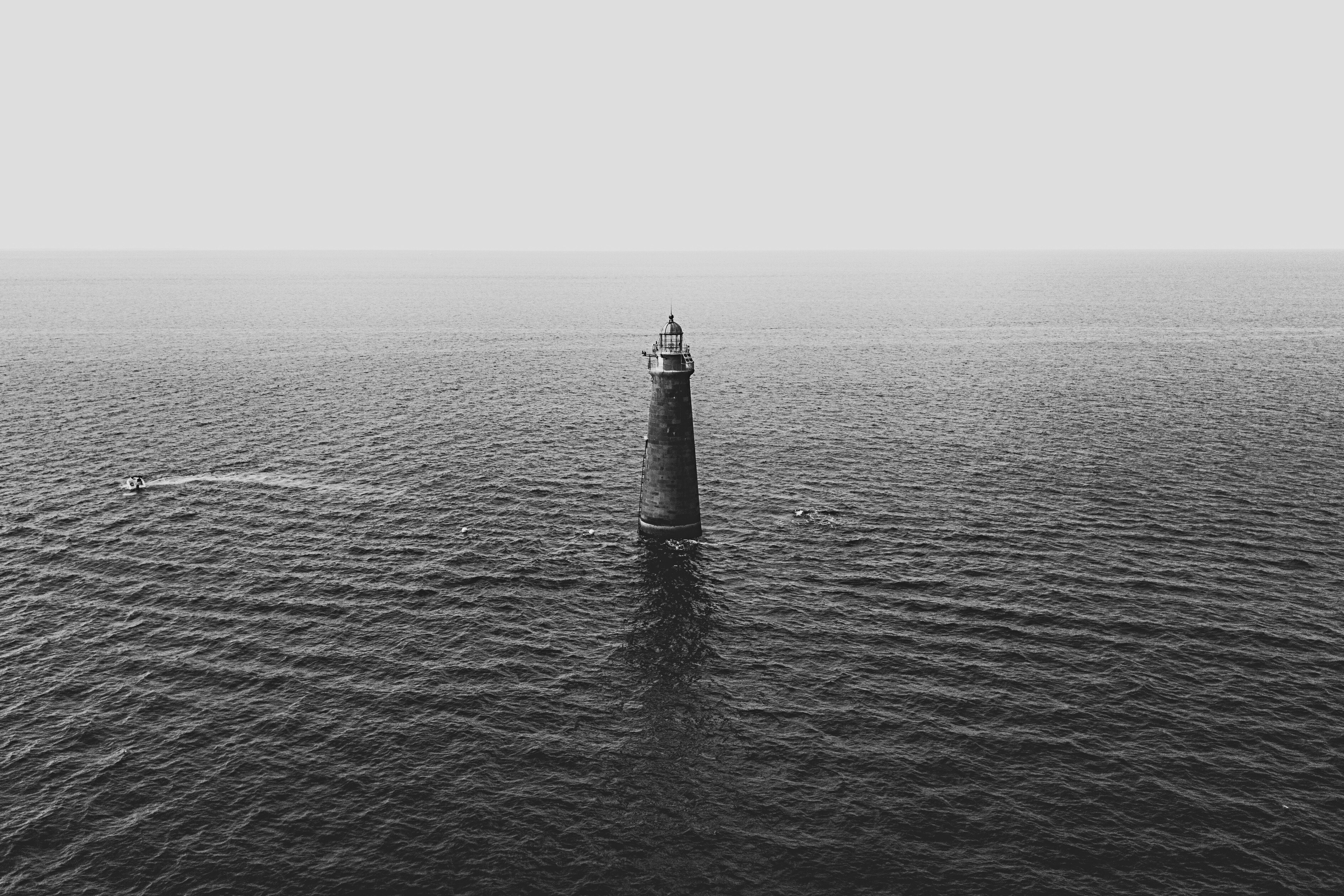 gray concrete lighthouse surrounded by ocean water